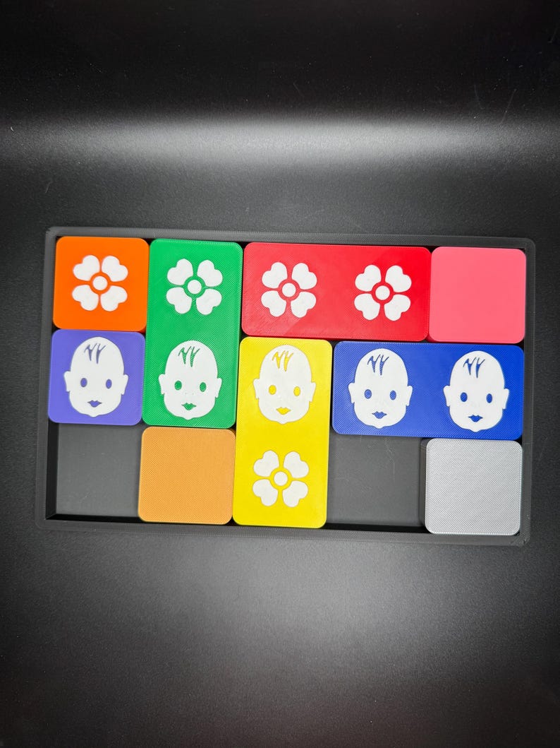 May include: A colorful puzzle with different shaped pieces. Each piece has a different image on it, including flowers and faces. The puzzle is made of plastic and is in a black frame.