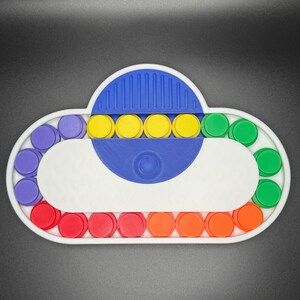 May include: A white cloud-shaped pop-it fidget toy with a blue center and rainbow colored circles around the edge. The toy has a variety of colors including purple, yellow, green, red, and orange.