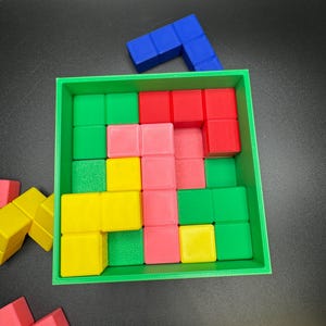 May include: A colorful puzzle game with a green square frame. The game includes red, pink, yellow, green, and blue blocks. Some blocks are inside the frame, and others are scattered around the frame.