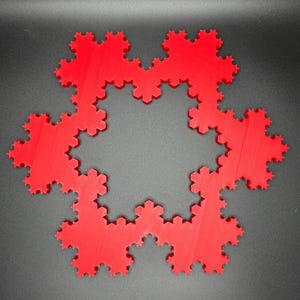 May include: A red 3D printed snowflake design with a circular shape and a detailed, intricate pattern.