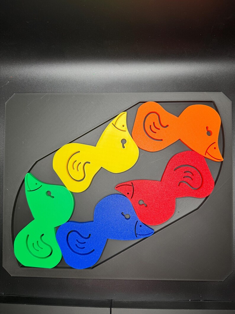May include: A colorful wooden puzzle featuring six duck-shaped pieces in green, blue, red, yellow, and orange. The puzzle pieces fit into a black rectangular base, designed for children's educational play.