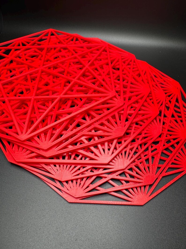 May include: A stack of red octagonal placemats with a geometric design. The placemats are made of a thin, flexible material and have a delicate, intricate pattern.