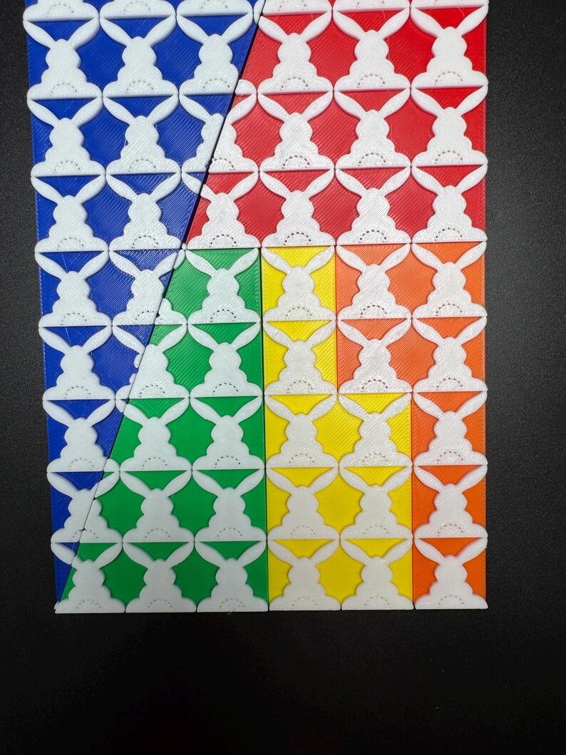 May include: A close-up of a colorful geometric pattern made of tiles. The tiles are arranged in a grid pattern and are colored blue, red, green, and yellow. Each tile features a white bunny rabbit design.