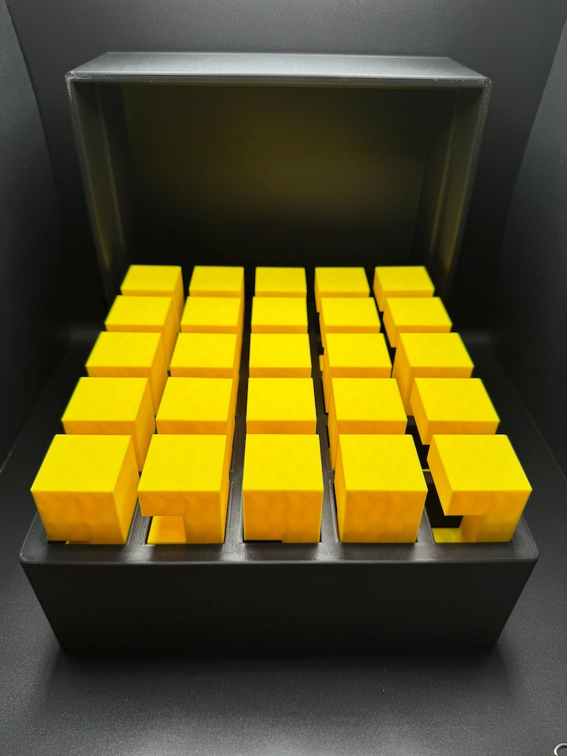 May include: A black box with a lid open, revealing a grid of 25 bright yellow cubes.