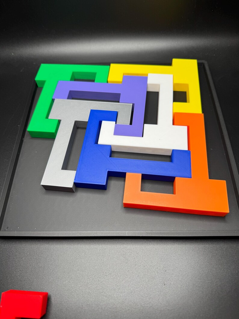 Op de afbeelding: Een kleurrijke puzzel met zeven stukken in verschillende vormen en kleuren. De stukken zijn in een patroon op een zwarte achtergrond gerangschikt.