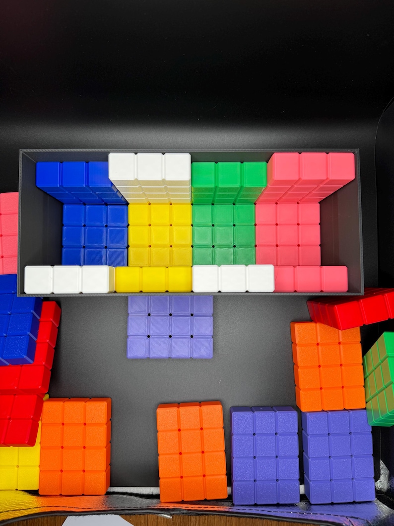 May include: A set of colorful plastic blocks in various shapes and sizes. The blocks are arranged in a pattern on a black surface. The blocks are red, blue, green, yellow, white, and orange.