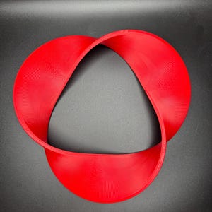 May include: A red, 3D printed, Mobius strip sculpture. The strip is twisted and forms a continuous loop.