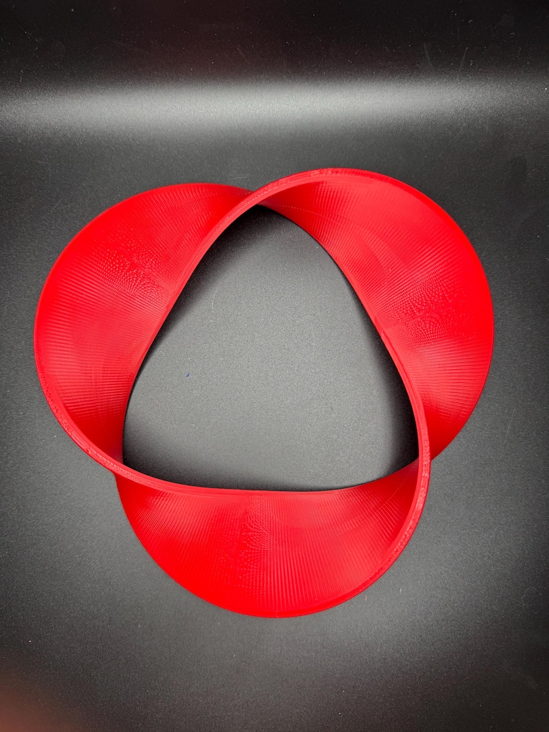 May include: A red, 3D printed, Mobius strip sculpture. The strip is twisted and forms a continuous loop.