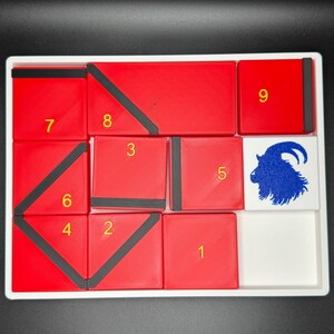 May include: A red and black puzzle with nine numbered squares and a white square with a blue goat illustration. The numbers 1 through 9 are visible on the red squares.