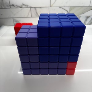 May include: A blue and purple building block structure with a red block on the side. The structure is made of small square blocks.