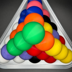 May include: A triangle-shaped rack holds a set of colorful billiard balls, including red, green, blue, yellow, orange, black, and white.