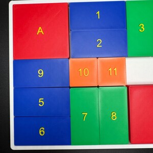 May include: A colorful puzzle with numbered and lettered tiles. The tiles are arranged in a grid pattern. The tiles are red, blue, green, orange, and white.