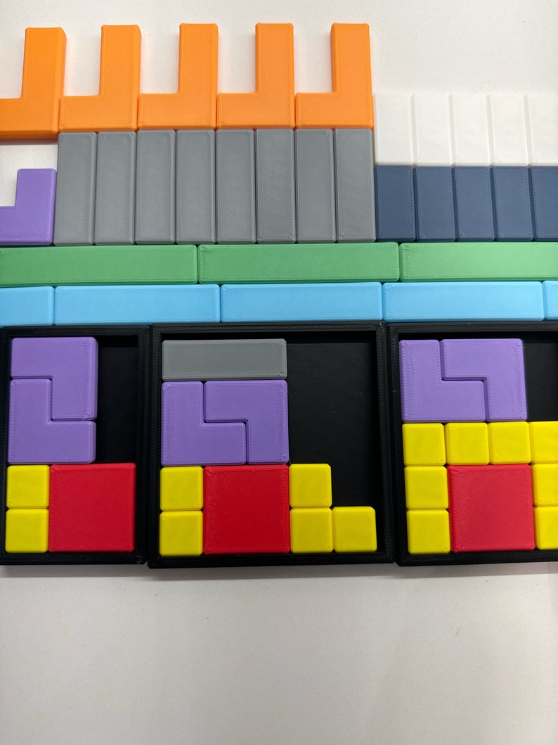 May include: A close-up of a puzzle game with three sections. Each section has a black frame and a different colored puzzle inside. The puzzles are made of small plastic squares in various colors, including red, yellow, purple, and gray.