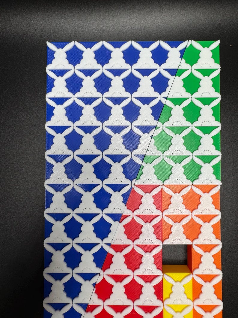 May include: A geometric pattern made of white plastic tiles with a bunny rabbit design. The tiles are arranged in a grid pattern and are colored blue, green, red, orange, and yellow.