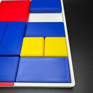 Op de afbeelding: Een wit dienblad met een verscheidenheid aan gekleurde blokken. De blokken zijn rood, blauw en geel. De blokken zijn in een patroon gerangschikt.