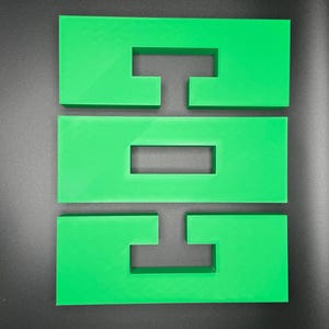 K&ouml;nnte beinhalten: Drei gr&uuml;ne Plastik-Puzzleteile, die &uuml;bereinander gestapelt sind. Jedes Teil hat eine andere Form, die aus der Mitte herausgeschnitten ist.