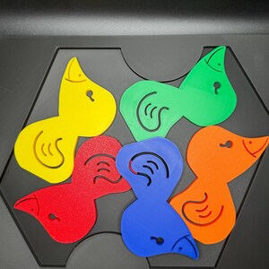 May include: A colorful puzzle featuring bird-shaped pieces in yellow, green, red, blue, and orange. Each piece has a unique design and fits into a black hexagonal base. The puzzle is designed for educational play.
