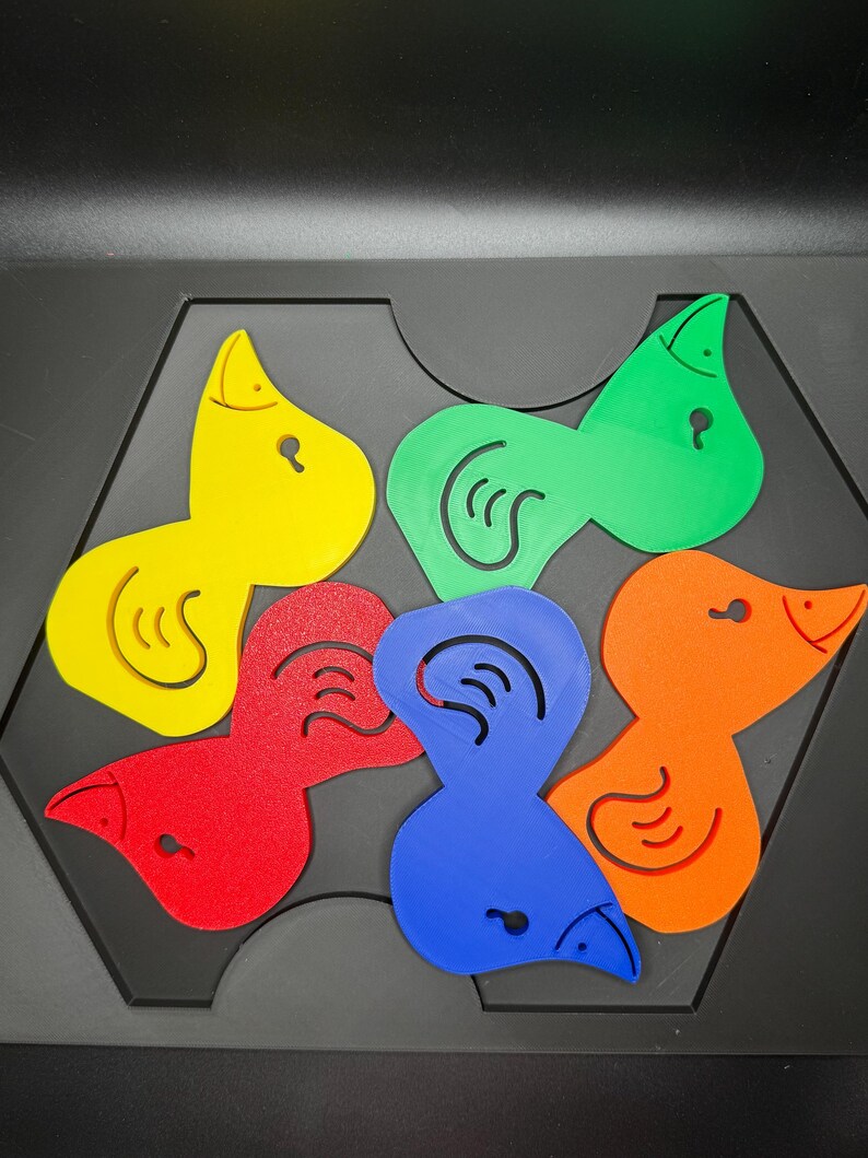 May include: A colorful puzzle featuring bird-shaped pieces in yellow, green, red, blue, and orange. Each piece has a unique design and fits into a black hexagonal base. The puzzle is designed for educational play.