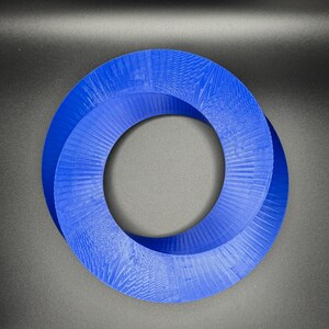 May include: A blue 3D printed Mobius strip, a continuous loop with a single twist, creating a unique geometric shape.