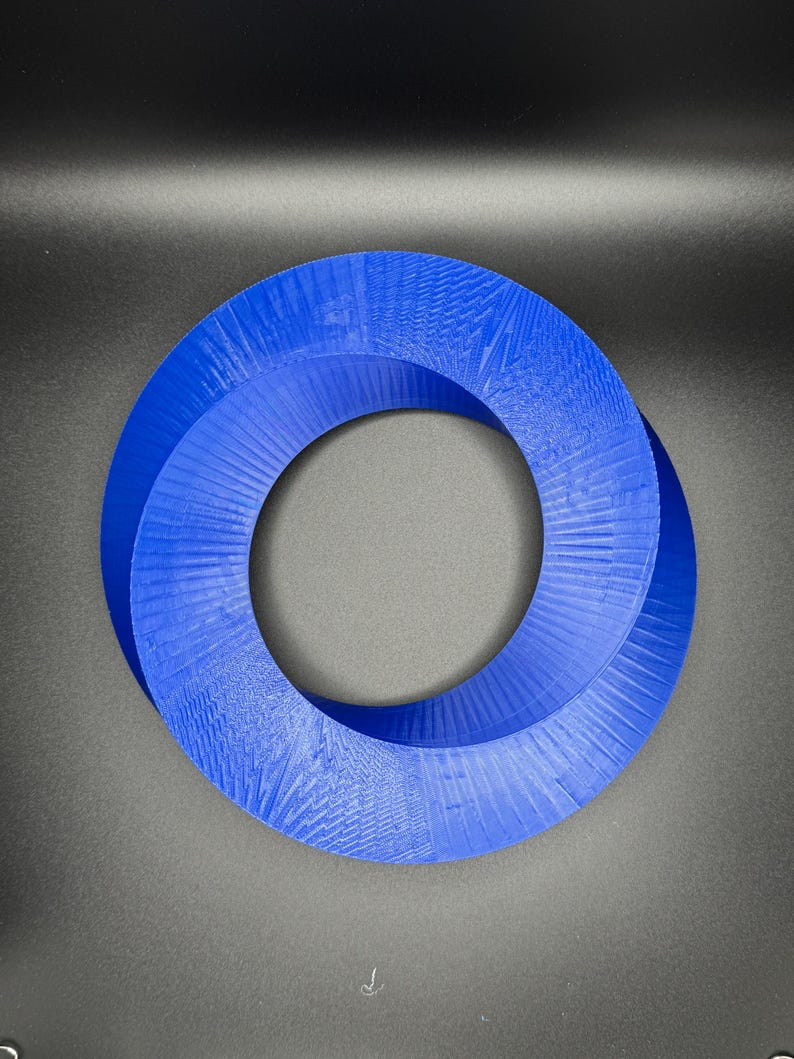 May include: A blue 3D printed Mobius strip, a continuous loop with a single twist, creating a unique geometric shape.