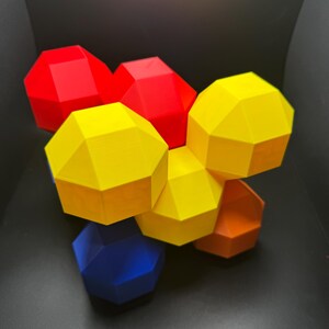 May include: A group of six geometric shapes, each with a different color. The shapes are red, yellow, blue, and orange. They are arranged in a cluster, with the yellow shape in the center.