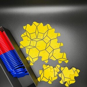 May include: A yellow geometric puzzle with black lines. The puzzle pieces are arranged in a circular pattern. The puzzle is in a black tray with blue and red puzzle pieces.