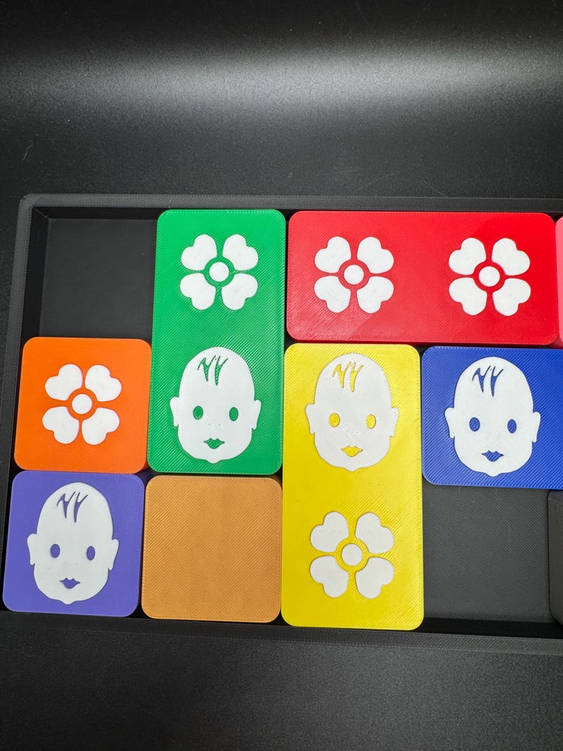 May include: Nine colorful square tiles with different images. The images include a flower, a baby face, and the letters "NY". The tiles are arranged in a grid pattern.