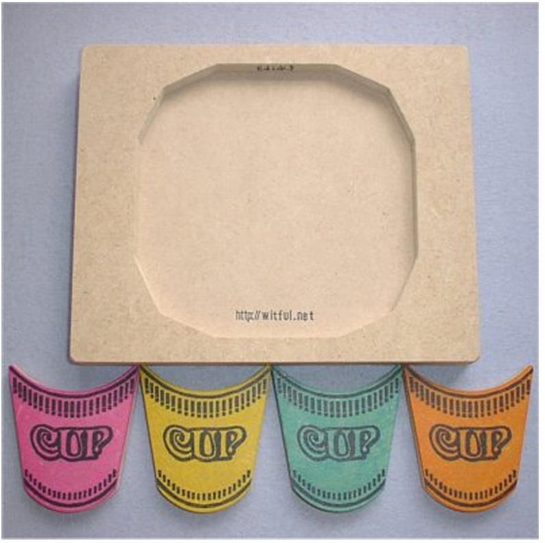 May include: A wooden frame with a circular cutout, accompanied by four colorful, cup-shaped cutouts. The cutouts are pink, yellow, teal, and orange, each with the word "CUP" printed on them. The website address "http://witful.net" is printed on the frame.