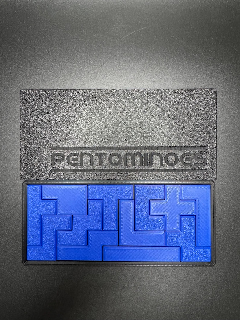 May include: A blue set of pentominoes in a black box with the word "PENTOMINOES" printed on the lid.