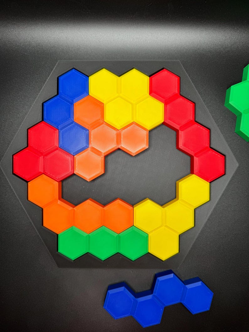 May include: A hexagonal puzzle with pieces in red, orange, yellow, green, and blue. The pieces are arranged in a circular pattern with a gap in the middle.