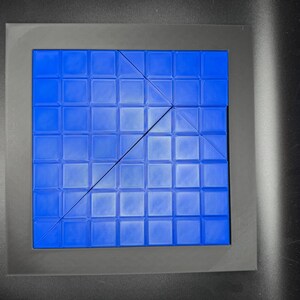 K&ouml;nnte beinhalten: Eine blaue quadratische Fliesenmatte mit einem Gittermuster. Die Matte ist durch eine diagonale Linie in zwei Dreiecke geteilt.