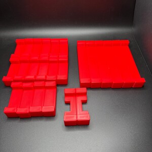 May include: Four red plastic building blocks, two are rectangular, one is square, and one is shaped like the letter 'H'.