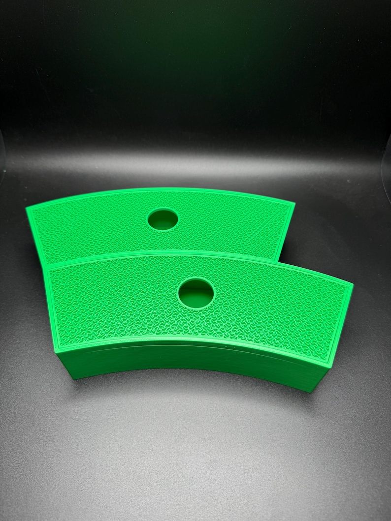 May include: Two bright green, curved, textured trays with a circular hole in the center. The trays are stacked on top of each other, with a dark background.