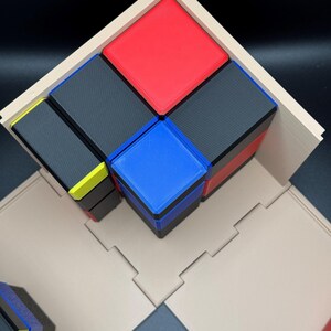 May include: A wooden frame holds a stack of colourful blocks. The blocks are arranged in a pyramid shape, with a red block on top, followed by a black block, then a blue block, and finally a black block on the bottom. The blocks are all the same size and shape.