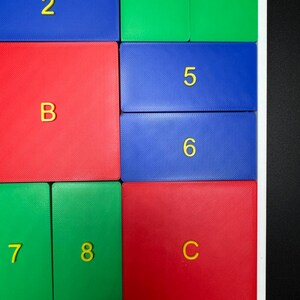 May include: A colorful puzzle with numbered and lettered tiles. The tiles are arranged in a grid pattern with red, blue, and green colors. The numbers 2, 3, 4, 5, 6, 7, and 8 are visible, along with the letters B and C.