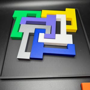 Op de afbeelding: Een houten puzzel met zeven in elkaar grijpende stukken in verschillende kleuren: groen, geel, paars, grijs, wit en blauw. De stukken zijn in een vierkante vorm op een zwart oppervlak gerangschikt.