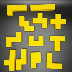 Puede incluir: Un conjunto de diez piezas de rompecabezas de pl&aacute;stico amarillo en forma de Tetris. Las piezas est&aacute;n dispuestas en una cuadr&iacute;cula sobre una superficie gris oscuro.