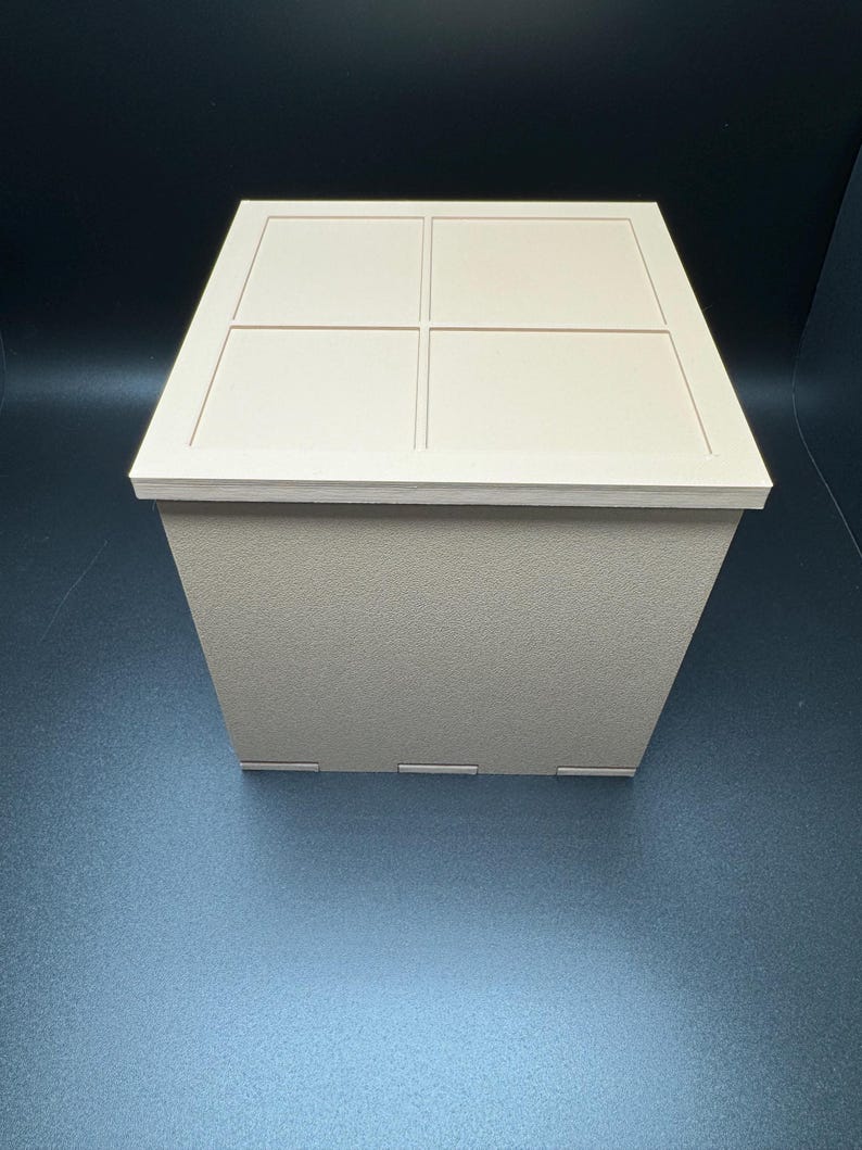 May include: A beige square box with a lid. The lid has four square indentations.