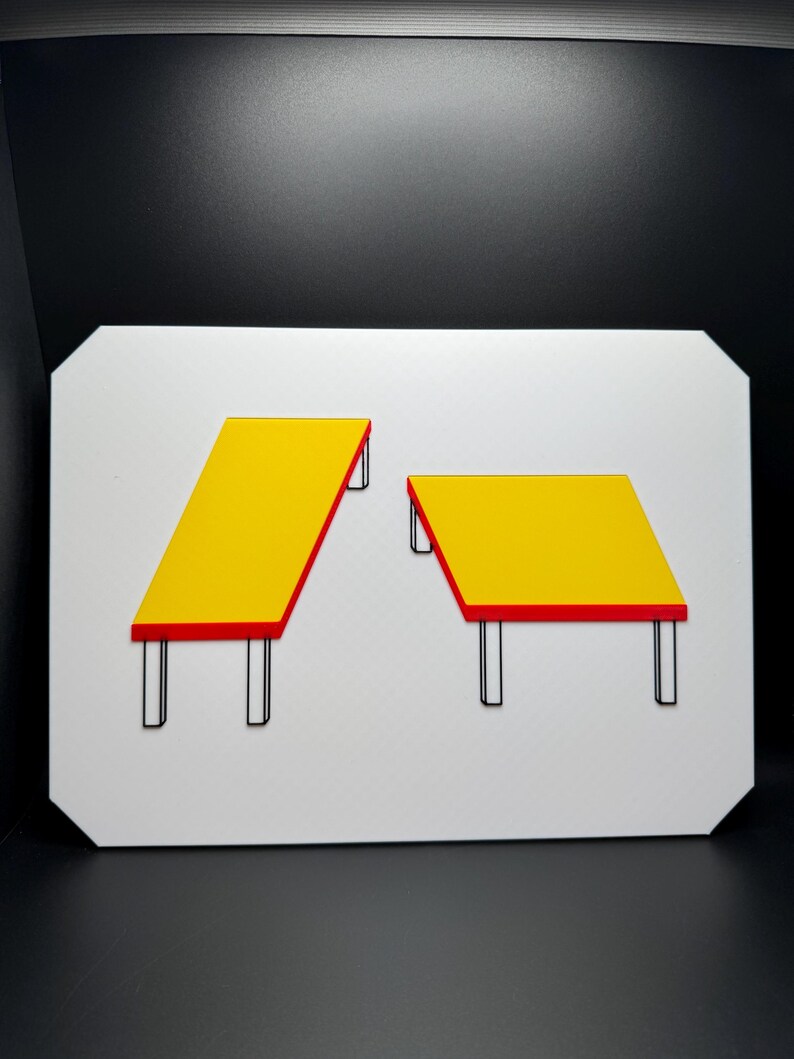 May include: A white rectangular sign featuring two yellow tables with red trim and black legs. One table is rectangular and angled, while the other is square. The background is black.