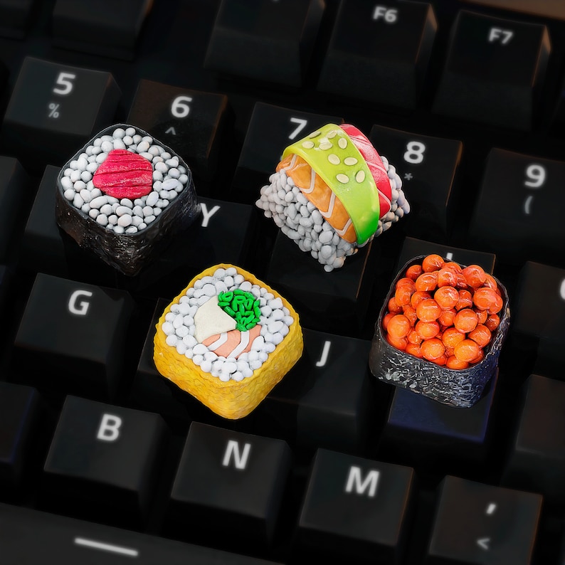 May include: Four different sushi rolls on a black keyboard. The rolls are made of rice, seaweed, and various fillings. The keyboard has keys labeled with letters and numbers.