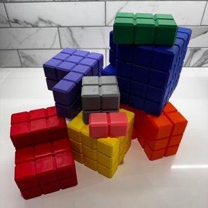 May include: A set of colorful, interlocking building blocks in various shapes and sizes. The blocks are made of a soft, flexible material and are perfect for creative play. The set includes red, blue, green, yellow, orange, and gray blocks.