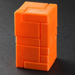 Puede incluir: Un rompecabezas 3D naranja con un dise&ntilde;o geom&eacute;trico. El rompecabezas est&aacute; hecho de piezas que se entrelazan y se pueden organizar de diferentes maneras.