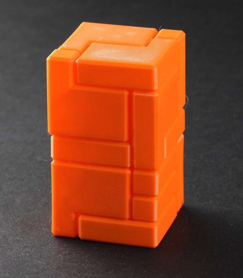 Puede incluir: Un rompecabezas 3D naranja con un dise&ntilde;o geom&eacute;trico. El rompecabezas est&aacute; hecho de piezas que se entrelazan y se pueden organizar de diferentes maneras.