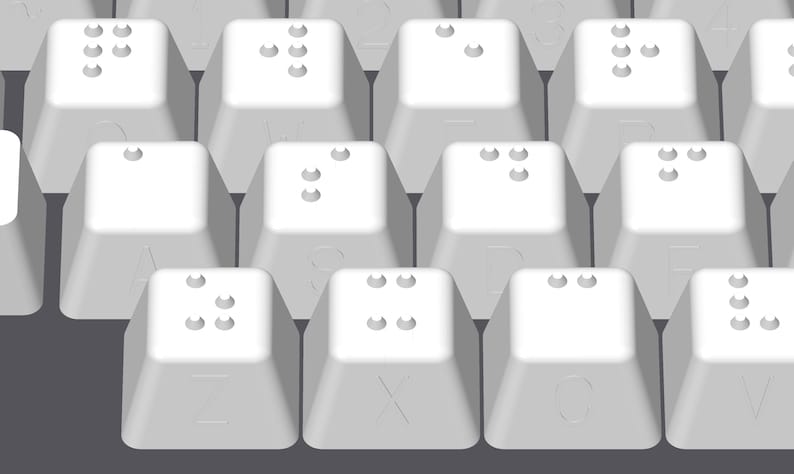 May include: A close-up of a white keyboard with braille lettering on the keys.