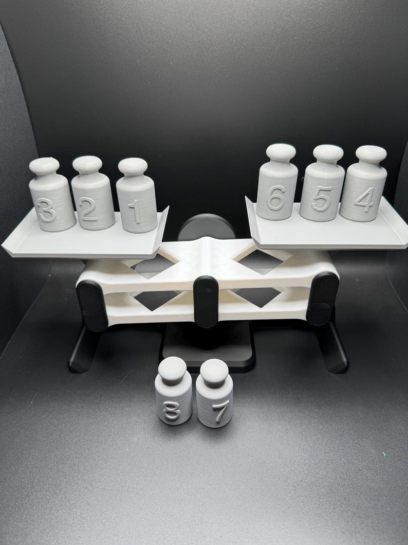 May include: A white balance scale with gray weights numbered 1, 2, 3, 4, 5, 6, 7, and 8. The scale is on a black surface.