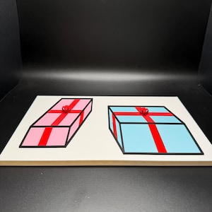 May include: A wooden puzzle featuring two gift boxes. One box is pink with a red ribbon, and the other is blue with a red ribbon. Both boxes have black outlines and are on a white background.