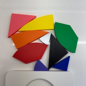 Op de afbeelding: Een set kleurrijke geometrische vormen, waaronder een roze driehoek, een gele halve maan, een oranje halve maan, een rode halve maan, een groene halve maan, een zwarte driehoek, een zilveren driehoek, een blauwe driehoek en een paarse halve maan.