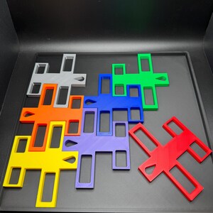 K&ouml;nnte beinhalten: Eine Sammlung farbenfroher, geometrischer Puzzleteile in verschiedenen Formen und Gr&ouml;&szlig;en. Die Teile sind in Rot-, Orange-, Gelb-, Gr&uuml;n-, Blau-, Lila- und Graut&ouml;nen gehalten. Die Puzzleteile sind auf einer dunklen Oberfl&auml;che angeordnet.