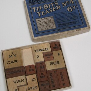 May include: A wooden puzzle game with 12 pieces, each with a number and a word printed on it. The words include "My Car", "Tramcar", "Rover", "Austin", "Bus", "Humber", "Bean", "Riley", "Swift", "Van", "Lorry", "Bentley", and "Singer". The puzzle is in a wooden box with a blue and white label that reads "Tit-Bits Teaser No. 4 6d".