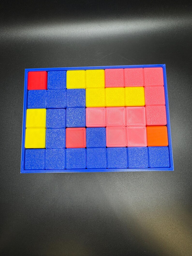 May include: A colorful puzzle game with a blue frame. The puzzle pieces are various colors, including red, yellow, pink, and orange. The game is designed with a grid of squares, and the pieces fit into the grid.